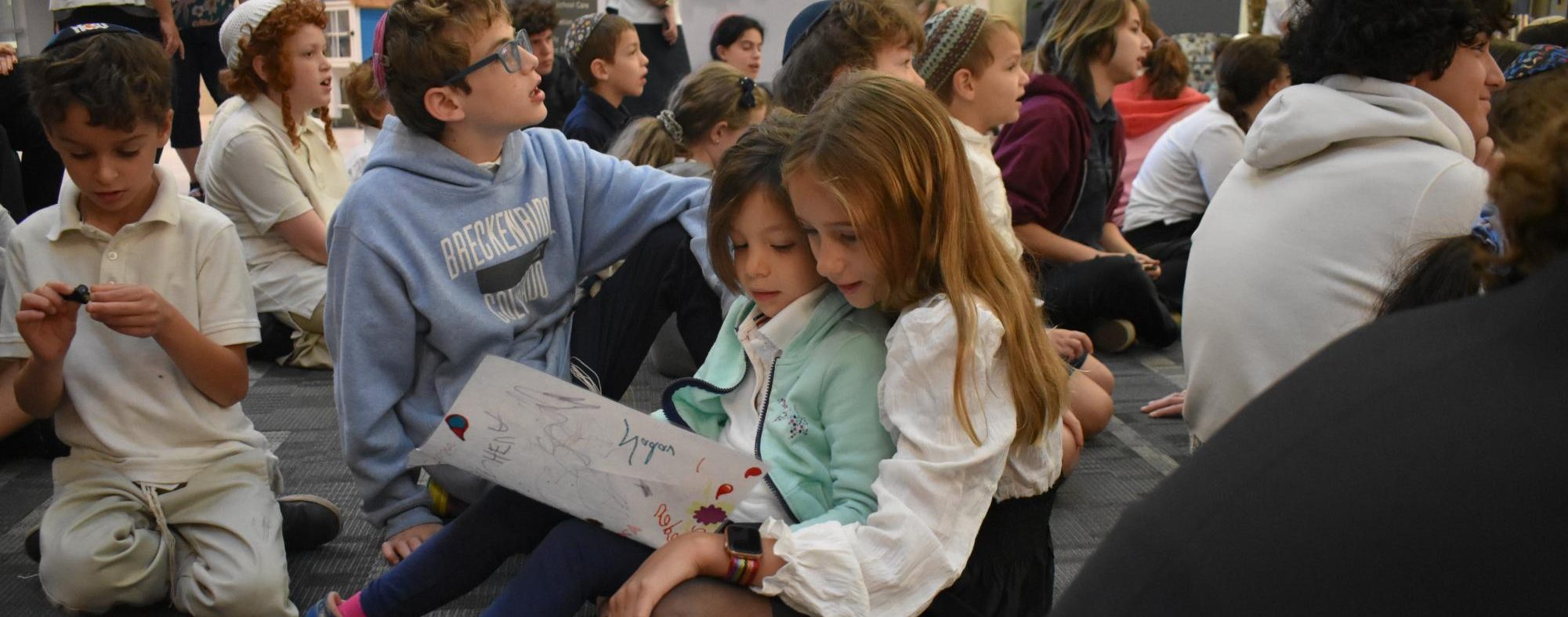 Sixth-grade student Ava Gordon holds first-grader Ellie Sandler on her lap during a family program.