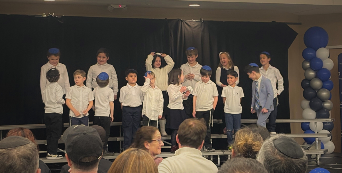 First graders stand on the risers conversing in between songs. Sometimes it gets difficult to be fully professional the whole way through the performance, especially as a first grader. Image by Naftali Tilove